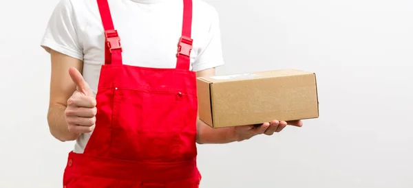 Mag szczęśliwy młody dostawca człowiek w czerwonej czapce stojący z paczki skrzynki pocztowej izolowane na białym tle. — Zdjęcie stockowe