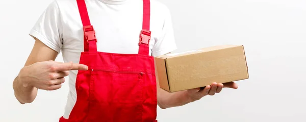 Mladý, usměvavý logistické doručovatel v červených uniformách krabici na bílém pozadí — Stock fotografie