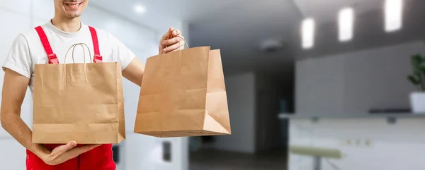 Dostawa, poczta i koncepcja ludzi - szczęśliwy człowiek dostarczanie żywności w jednorazowej torbie papierowej do domu klienta — Zdjęcie stockowe