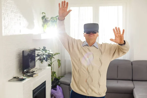 Elderly man wearing a Virtual Reality glasses at home — Stock Photo, Image