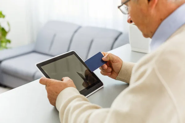 Uomo anziano al computer portatile che paga con carta di credito per lo shopping online — Foto Stock