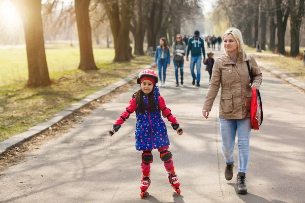 Moeder en haar dochter dragen rolschaatsen in het park — Stockfoto