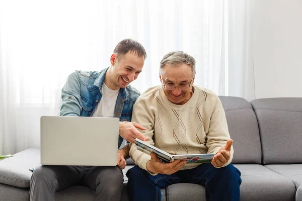 Gamla far läsa tidningen och hans son med tablett — Stockfoto