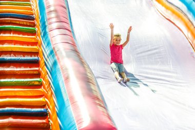 Bir şişme kaydıraktan kayar küçük kız