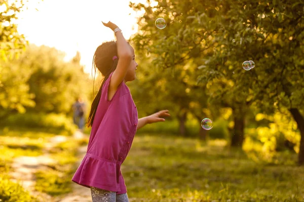 Children girl blowing soap bubbles in outdoor forest — Stock Photo, Image