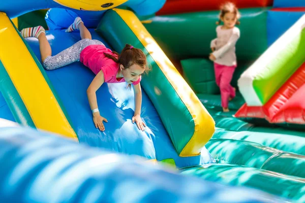 Criança pulando no trampolim playground colorido. As crianças saltam no castelo inflável do salto na atividade da festa de aniversário do jardim de infância e no centro do jogo para a criança pequena. Menina brincando ao ar livre no verão — Fotografia de Stock