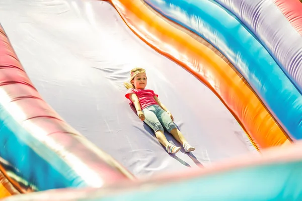 Petite fille glissant vers le bas une glissière gonflable — Photo