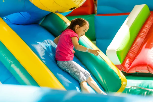 Menina deslizando para baixo uma corrediça inflável — Fotografia de Stock