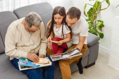 Akrabaların evinde aile fotoğraflarına bakıyorlar.