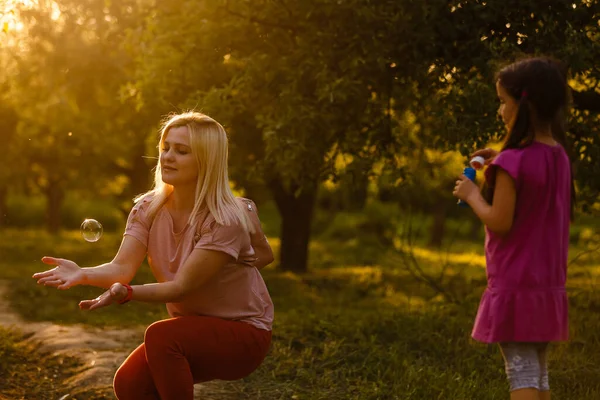 Mom and daughter blow bubbles on sunset — 스톡 사진