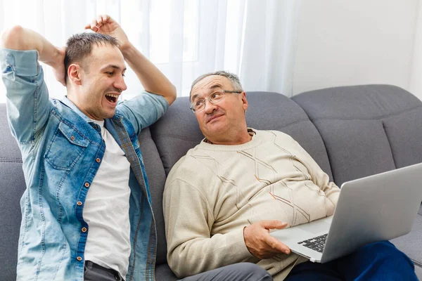 Yaşlı baba ve oğlu kanepede oturup dostça sohbet ediyorlar.