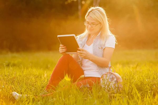 Parkta oturup kitap okuyan memnun bir kadın.