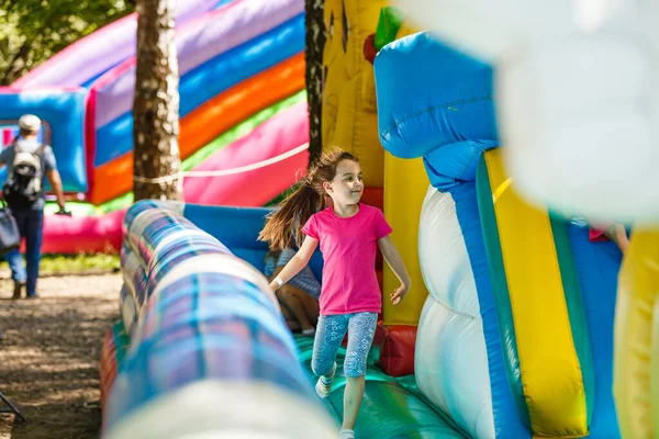 Menina feliz ter muita diversão em um castelo de salto durante o deslizamento. — Fotografia de Stock