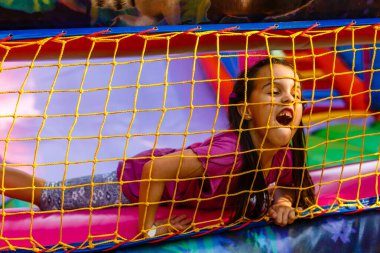 Neşeli bir çocuk şişme bir kalede oynuyor.