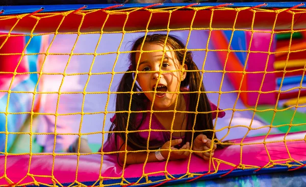 Menina feliz ter muita diversão em um castelo de salto durante o deslizamento — Fotografia de Stock