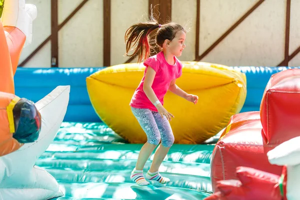 カラフルな遊びトランポリンでジャンプの子。子供は幼稚園の誕生日パーティー活動インフレータブル バウンス城に飛び込んで、若い子供のためのセンターを再生します。夏に野外で遊ぶ少女 — ストック写真