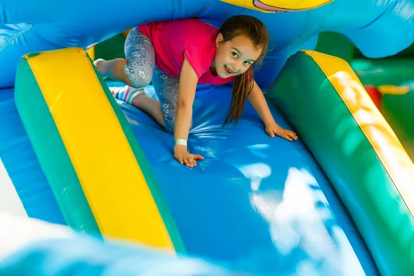 Klein meisje glijdend van een opblaasbare glijbaan — Stockfoto