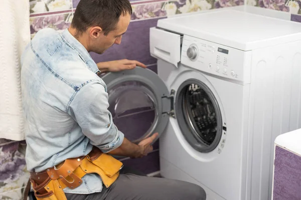 Homem repara uma máquina de lavar roupa — Fotografia de Stock