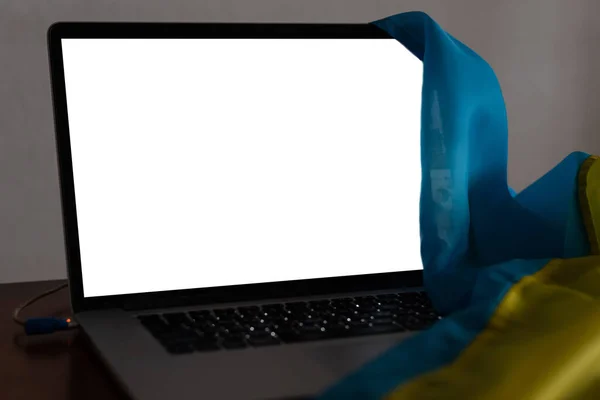 Laptop com tela em branco na mesa e bandeira nacional ucraniana no fundo, espaço para texto. — Fotografia de Stock