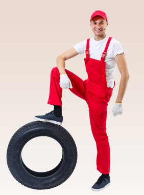 Çalışan adam beyaz arka planda bir lastik tutuyor.