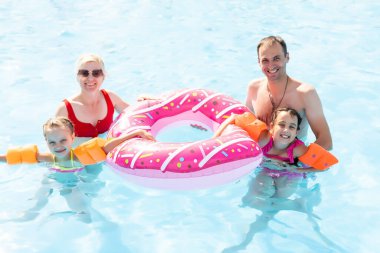 Havuzda mutlu bir aile, suda eğleniyor, çocuklu bir anne su parkında eğleniyor, plaj tatili, yaz tatili, tatil konsepti.