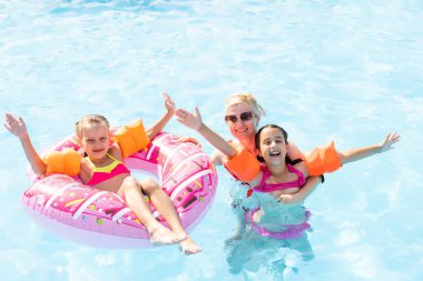 Denizde tropik bir tatil köyünde mavi yüzme havuzunda oynayan mutlu bir aile. Yaz tatilleri konsepti.
