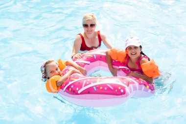 Denizde tropik bir tatil köyünde mavi yüzme havuzunda oynayan mutlu bir aile. Yaz tatilleri konsepti.