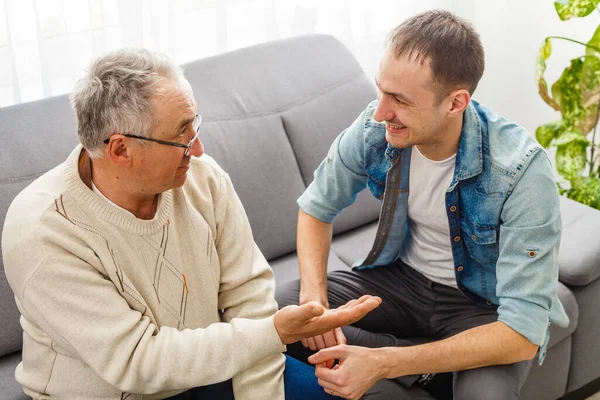 Glad pensionerad man och vuxen son pratar hemma — Stockfoto