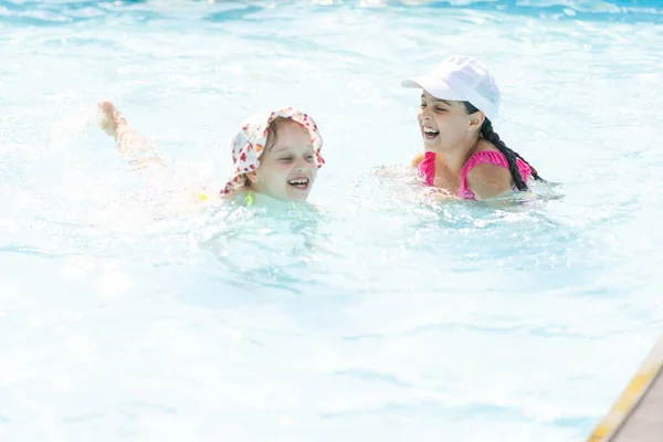 Deux filles éclaboussent dans une piscine extérieure en été. Enfants heureux, soeur jouer, profiter du temps ensoleillé dans la piscine publique — Photo