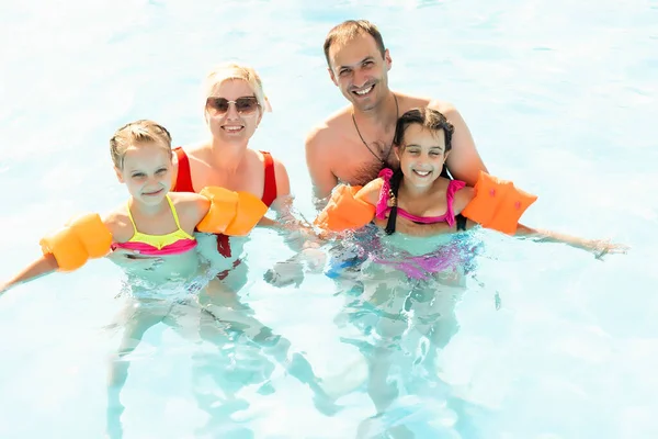 Familia feliz divirtiéndose en las vacaciones de verano, jugando en la piscina. Concepto de estilo de vida saludable activo — Foto de Stock