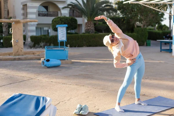 Fitness, sport, persone e stile di vita sano concetto - donna che fa yoga nel signore della danza posa sul tappeto sulla spiaggia e piscina sfondo . — Foto Stock