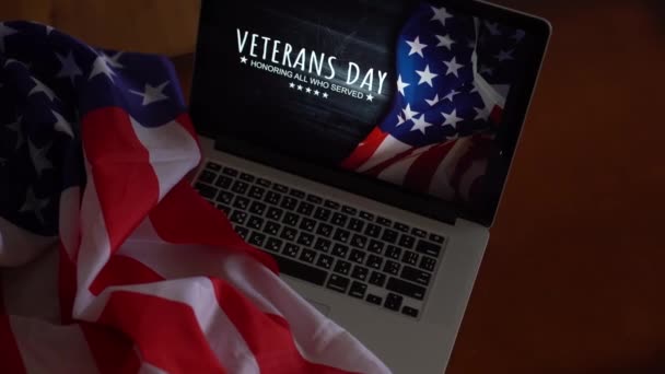 Dzień weteranów napisany w laptopie z flagą Stanów Zjednoczonych, na rustykalnym drewnianym tle — Wideo stockowe