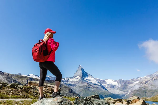 Yürüyüşçü kadın. Sırt çantasıyla yürüyüşe çıkmış. Sağlıklı ve aktif bir yaşam tarzı var. İsviçre 'nin İsviçre Alpleri' nde dağ manzarasında yürüyüş yapan yürüyüşçü kız.. — Stok fotoğraf