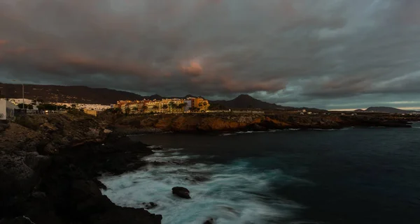 Panoramatický pohled Las Americas osvětlené v noci proti barevné západu slunce na obloze se světly na obzoru na ostrově Tenerife, Španělsko — Stock fotografie