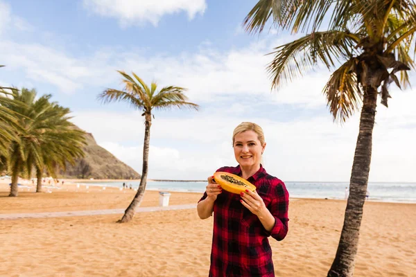Frau posiert in Palmenblättern auf einer Insel mit tropischen Früchten in der Hand — Stockfoto