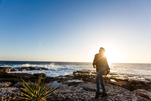 Volkanik kayalıklardaki kadınlar ve dalgalı mavi okyanus, beyaz köpük ve volkanik kayalar. Kanarya Adaları. Atlantik Okyanusunun muhteşem kıyıları