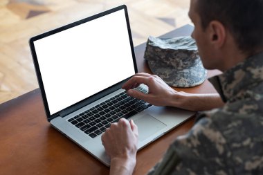 Ordu. Siyah arka planda boş ekranı olan bir dizüstü bilgisayarla çalışan genç asker..