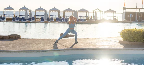 Buongiorno con yoga che medita sullo sfondo dell'alba. Donna attiva che pratica a bordo piscina per mantenersi in forma e in salute. Allenamento fitness femminile, attività sportiva durante le vacanze estive in famiglia. — Foto Stock