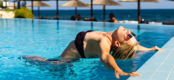 Egy fiatal nő, aki a nyári szünetben a medencében pihen. Szőke, fehér. — Stock Fotó