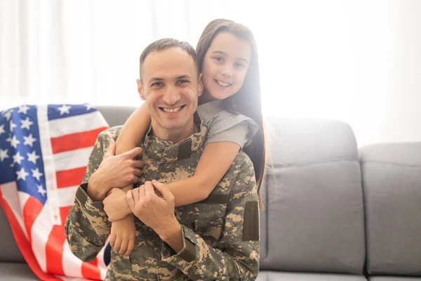 Filha menina feliz com bandeira americana abraçando pai em uniforme militar voltou do exército dos EUA, soldado masculino reunido com a família em casa — Fotografia de Stock