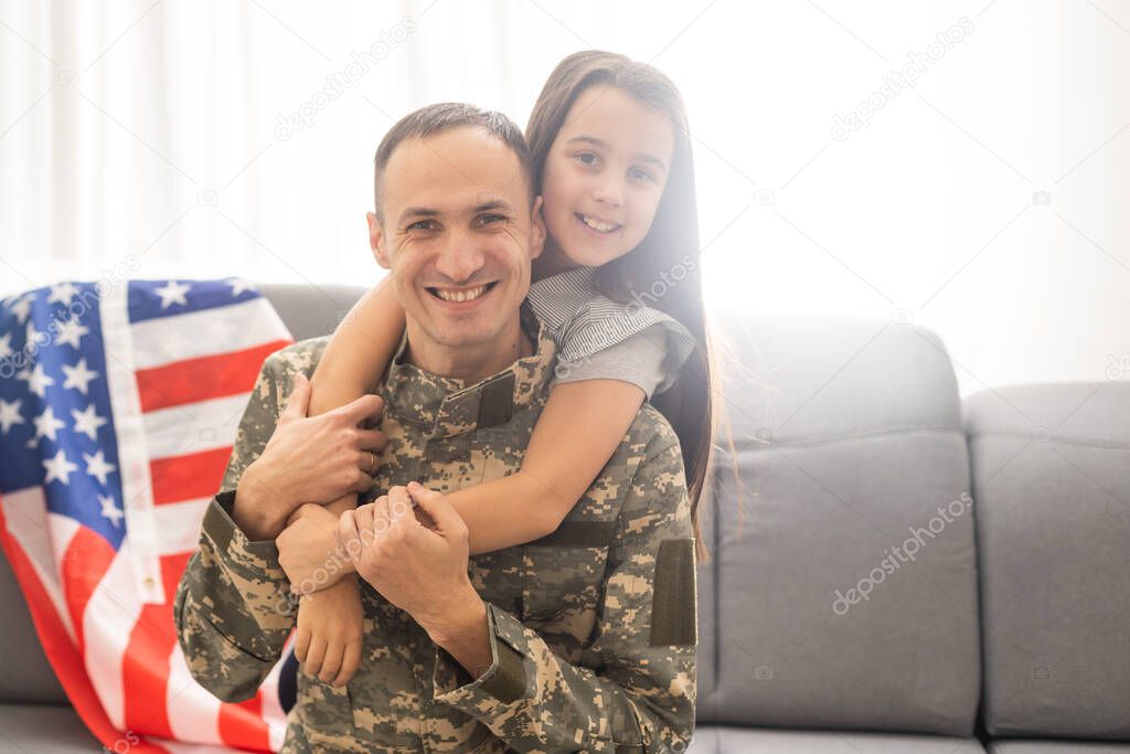 Happy little girl daughter with American flag hugging father in military uniform came back from US army, male soldier reunited with family at home