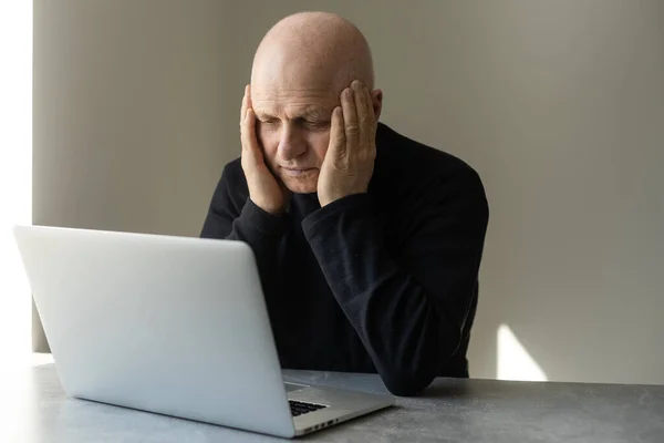 Bezorgd senior man met laptop thuis — Stockfoto