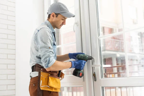 Man fixing lock to window with electric screwdriver — Stock Photo, Image