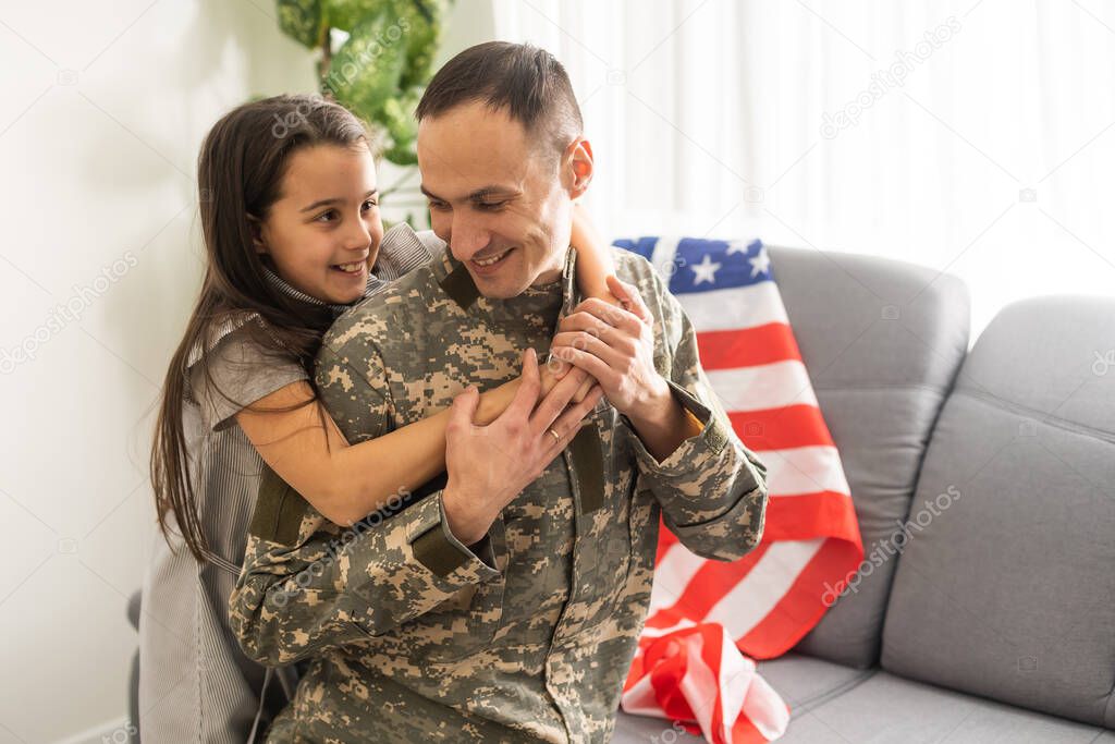 a child girl hugs a military father. dad in military uniform with his daughter. the veterans return to the family