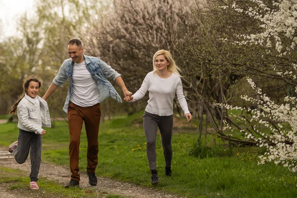 Mutlu genç aile dışarıda yeşil doğada birlikte vakit geçiriyor.