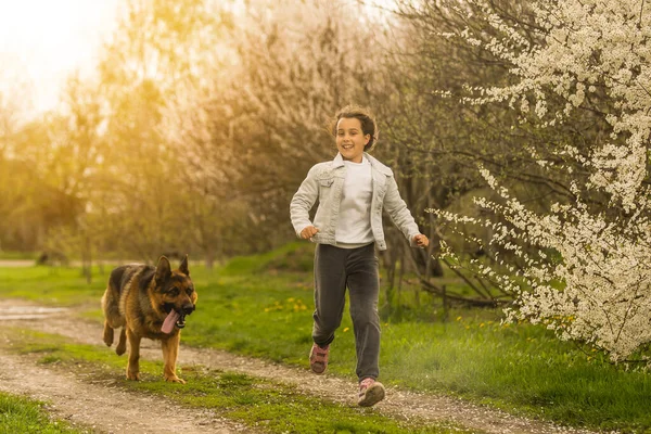 Menina correndo com um cão em um jardim de flores — Fotografia de Stock
