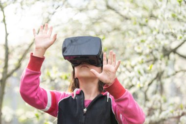 Sanal gerçeklik kulaklığı olan bir çocuk evde doğal hayatın arkasında oturuyor..