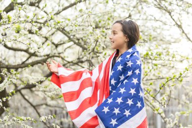 Gülümseyen ve Amerikan bayrağı sallayan sevimli küçük kız. Vatansever bayram. Mutlu çocuk, Amerikan bayrağı taşıyan şirin küçük kız çocuğu. ABD 4 Temmuz 'u kutluyor. Bağımsızlık Günü kavramı.