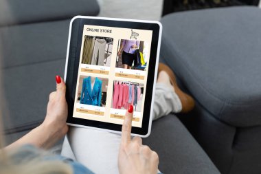 Çevrimiçi mağazada dijital tablette kıyafet arayan kadın
