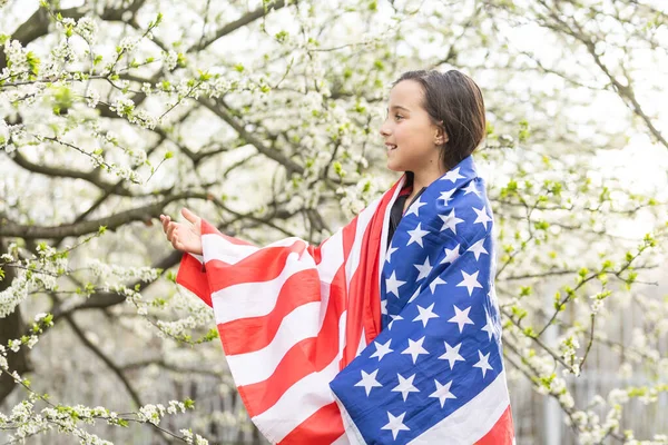 미소짓고 미국 국기를 흔들며 행복해 하는 귀여운 소녀. 국경일. 행복 한 꼬마 미국 국기를 든 귀여운 꼬마 소녀. 미국은 7 월 4 일 을 축하 한다. 독립일의 개념. — 스톡 사진